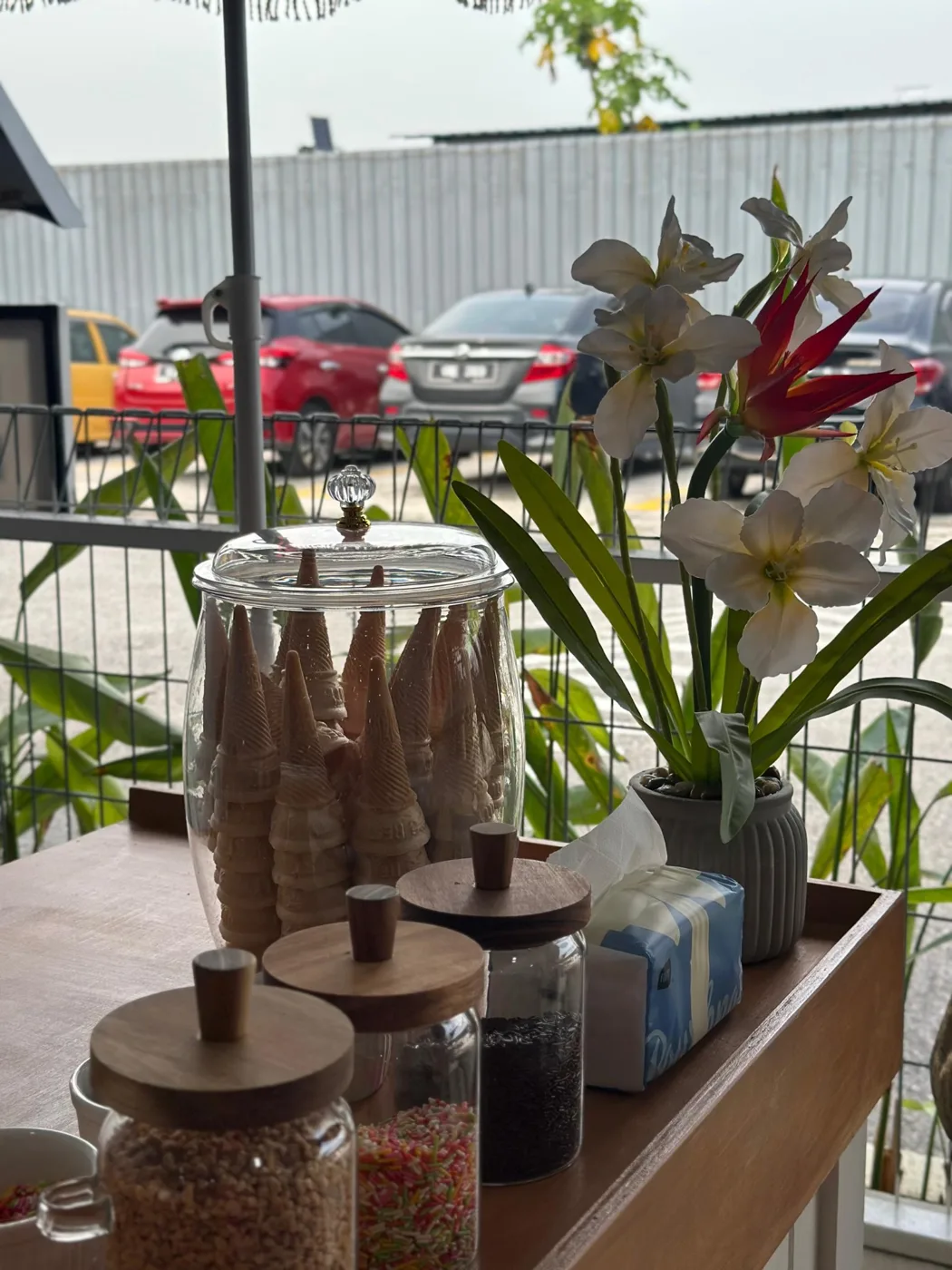 Glass cone jar and topping jars beside white floral decorations