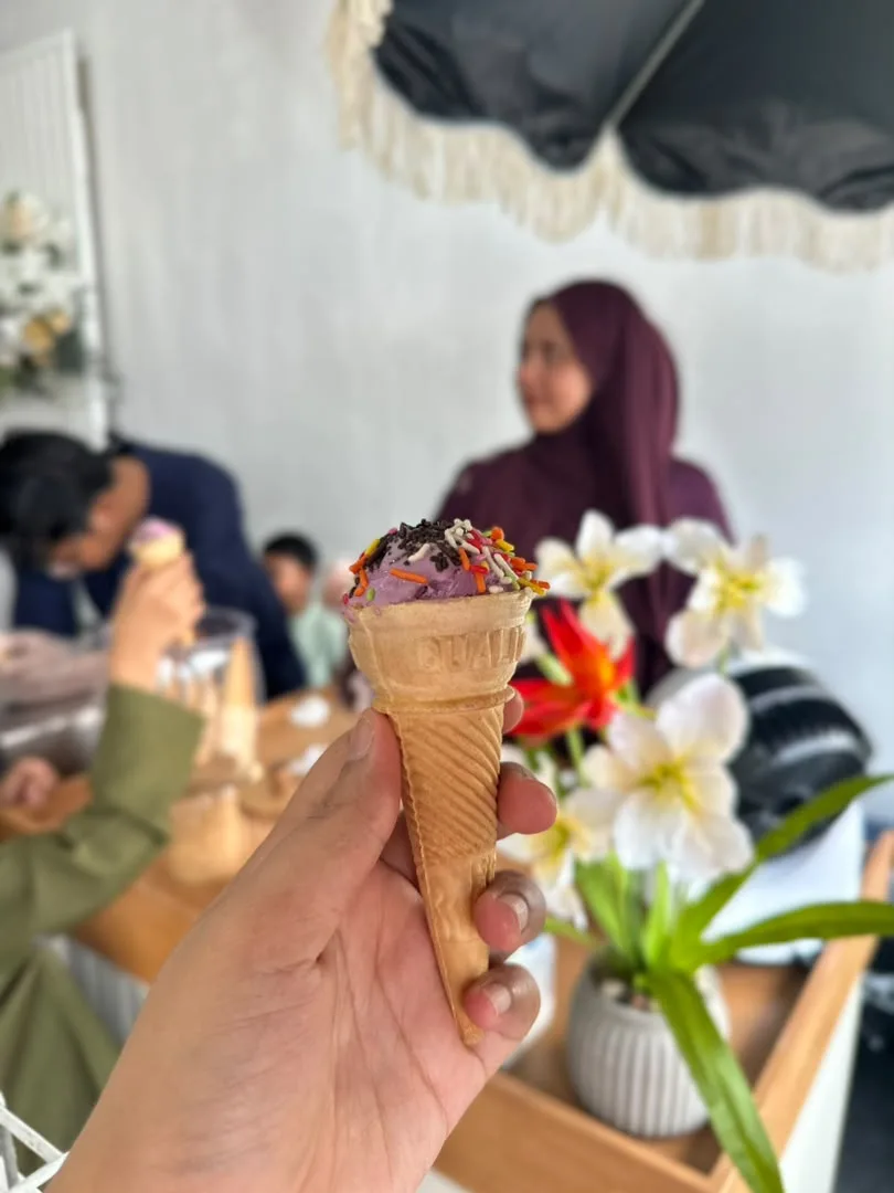 Ice cream cone topped with chocolate and rainbow sprinkles at an event