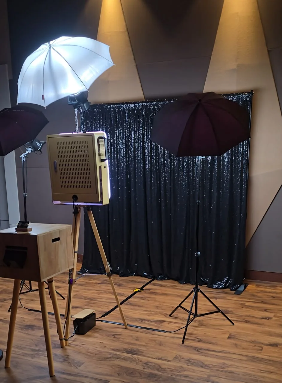 Wooden tripod photobooth with umbrella lighting and black sequin backdrop
